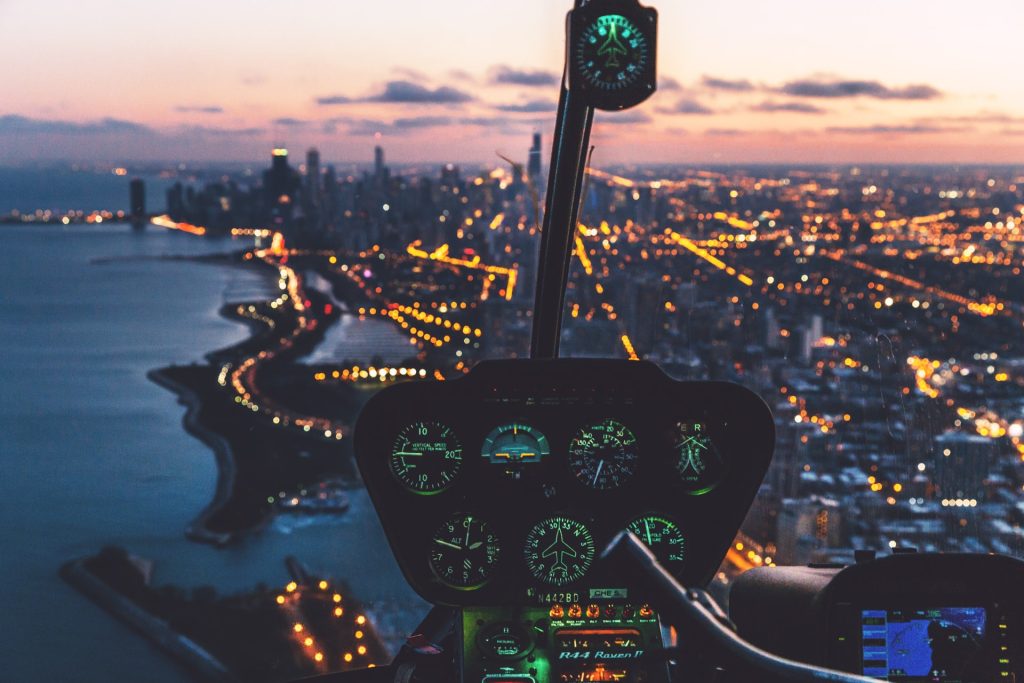 Blick aus einem Helikoptercockpit auf eine leuchtende Stadt bei Sonnenuntergang – Sinnbild für datenbasierte Steuerung und klare Entscheidungsgrundlagen in Mediaagenturen mit Digital Control.